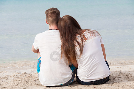 夏天坐在沙滩上的浪漫的年轻情侣友谊海洋蓝色男人女孩恋人幸福旅游男性海岸图片