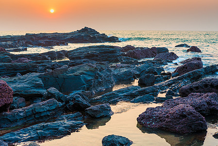 日落时美丽的海景和岩石海岸图片