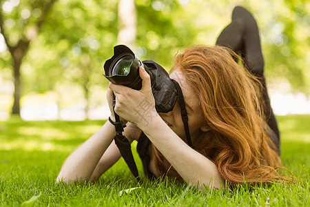 在公园的女摄影师草地绿地女性闲暇摄影单反说谎技术相机长发背景图片