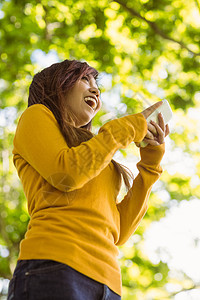 美丽的年轻女子在公园里发短信沟通绿地微笑橙子拨号手机电话快乐草地短信图片