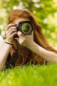在公园的女摄影师女性绿地镜片技术相机闲暇爱好摄影单反说谎背景图片