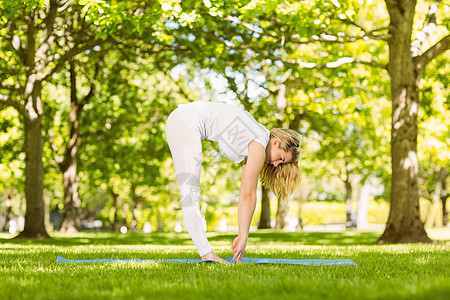 在公园里做瑜伽的平和金发美女脚趾调子蓝色快乐微笑金发女郎阳光运动服女性女士背景图片