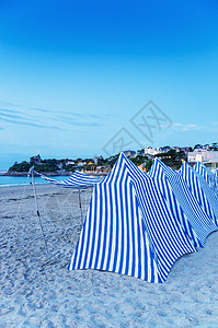 日落时沙滩上的白色和蓝色帐篷图片