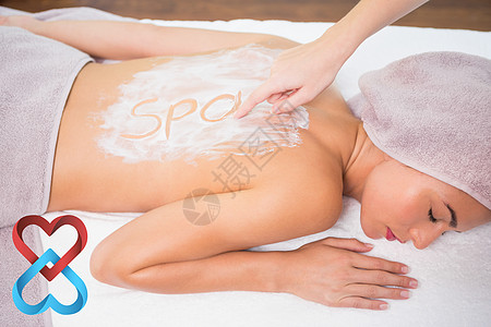 具有吸引力的妇女在温泉中心接受背面防晒霜的综合形象图片