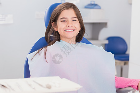 坐在牙医椅子上的年轻病人笑容口腔围兜诊所健康童年医疗女性女孩设备考试图片