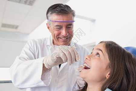 使用牙线为年轻病人提供儿科牙医服务医学女孩保健童年男性考试围兜手术实验微笑图片