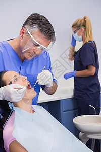 身戴面罩和检查病人的牙医图片