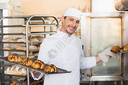 手持牛角面包盘的微笑面包师餐厅男性餐饮厨师工业面包烤箱白人制服手套图片
