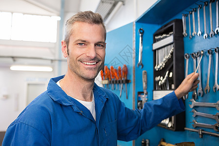 从墙上取工具的机械工程师工人微笑修理男性男人汽车车库机械师架子图片