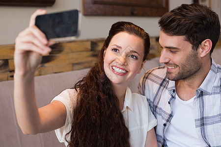 在约会时玩自拍的可爱情侣技术青少年咖啡馆拍照行业夫妻快乐男性手机活动图片