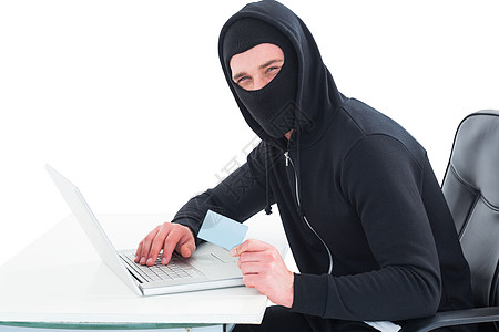 使用笔记本电脑和信用卡的黑客技术男性兜帽电子商务身份骇客桌子网站网络办公椅图片