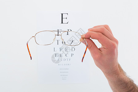 手握眼镜进行眼视测试配镜师眼睛考试身体检查技术医院听诊背景图片