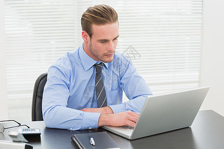 利用笔记本电脑集中经营的商务人士桌子计算器眼镜旋转椅领带男人专注职场办公室人士图片