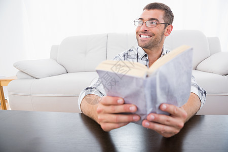 一个笑着看书的男人沙发家庭生活地板微笑家庭客厅文学阅读男性页数图片