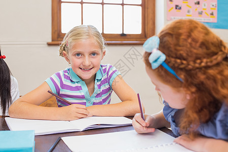 在课堂桌上写字的可爱学生金发女郎教育女孩女性小学生桌子金发瞳孔快乐学习图片