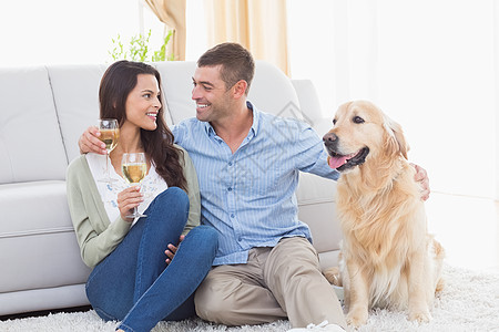 夫妇在与狗同坐时持有葡萄酒杯白酒家庭生活房子客厅女士微笑快乐沙发宠物女性图片