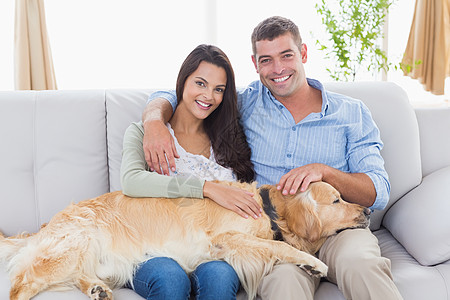 桔钓沙坐在沙发上 一对快乐的情侣在沙发上钓狗背景