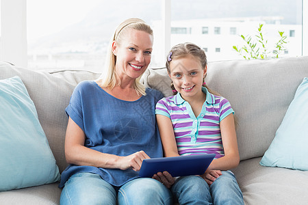 幸福的母亲和女儿在沙发上使用数字平板电脑图片