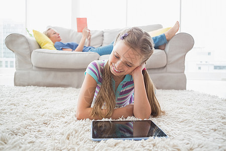 快乐女孩在客厅地毯上使用数字平板电脑图片