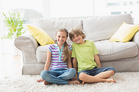坐在客厅地毯上的幸福兄弟姐妹的肖像图片
