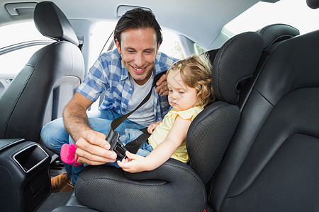 父亲保护婴儿在汽车座椅上微笑女性团结车辆后座家庭女儿孩子公路旅行图片