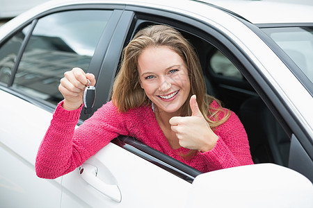 年轻女人笑着拿着钥匙车辆手势双手窗户公路粉色女士闲暇司机代理商图片