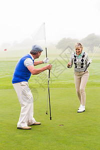 高尔夫情侣欢呼着绿色运动员胜利微笑夫妻推杆闲暇女性成功老年男性背景图片