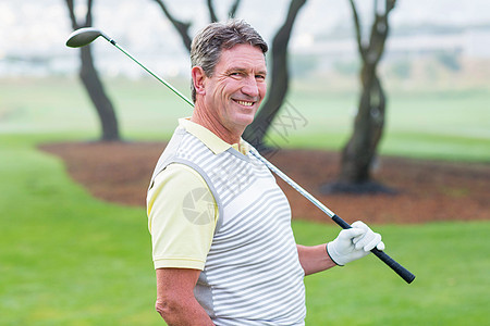 高尔夫球手站着挥舞着他的俱乐部 在镜头下微笑男人毛衣运动员男性绿色老年休闲活动黑色背心图片