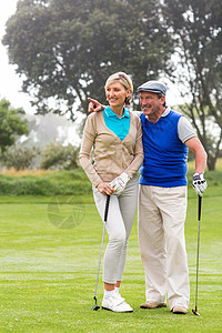 高尔夫夫妇走在绿色的路上运动员毛衣运动闲暇互动活动微笑时间老年服装背景图片