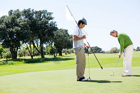 Golfer 为朋友投球持洞旗手套假期运动员爱好闲暇高尔夫高尔夫球推杆专注旗帜图片