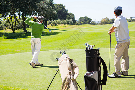 Golfer 为朋友投球持洞旗活动高尔夫专注运动员假期闲暇老年友谊旗帜晴天图片