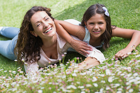 幸福的母亲和女儿躺在草地上家长头发女性院子晴天孩子服装家庭闲暇女孩图片