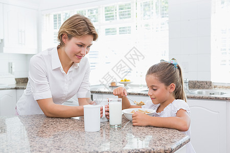 母亲和女儿吃早饭厨房微笑快乐感情女孩女性谷物早餐牛奶闲暇图片