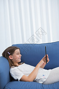 小女孩在沙发上使用数字石板头发公寓平板住所女孩服装休闲电脑触摸屏家庭生活图片