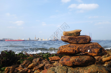 海洋沿岸的岩石棕色天空海滩石头卵石蓝色海藻船厂图片