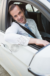 英俊的商务人士对着镜头微笑汽车公路零件代理商窗户套装领带衬衫司机运输图片