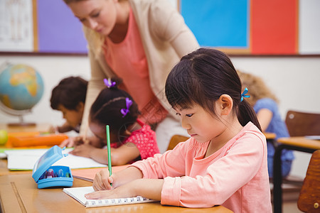 在课堂桌上写字的可爱学生女士写作工作开襟衫桌子瞳孔同学们教学笔记本班级图片