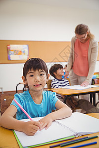 在课堂桌上写字的可爱学生学校椅子黑板职业绘画小学生教育男性记事本老师图片