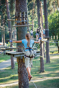 女孩在一个攀登冒险公园绳索安全勇气力量孩子森林自由行动闲暇成功图片