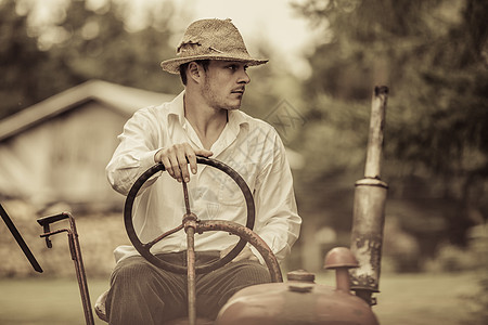 年轻农民在旧式拖拉机上牧场主草帽机械谷仓男人机器居民司机农场乡村图片