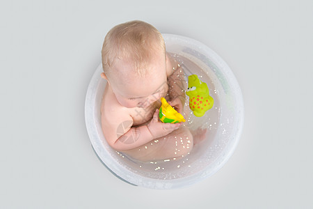 可爱的婴儿在透明桶里洗澡和玩耍浴缸女孩孩子皮肤新生沐浴鳄鱼玩具神童乐趣图片