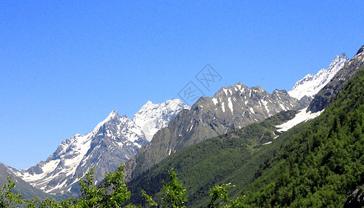 白雪和清蓝天空下高加索山脉石头森林滑雪季节岩石天蓝色旅行冻结高山爬坡图片