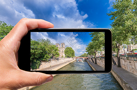 男性手与智能手机拍摄巴黎和 Notre Da的照片图片