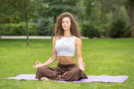 做瑜伽锻炼的漂亮女人女性训练冥想有氧运动头发微笑公园草地享受女士图片
