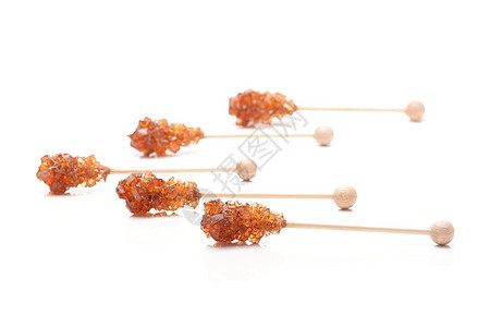 木棍上的棕色糖晶体 在白色背景上隔绝琥珀色糖类颗粒状甜点木头粮食焦糖糖果水晶蔗糖图片
