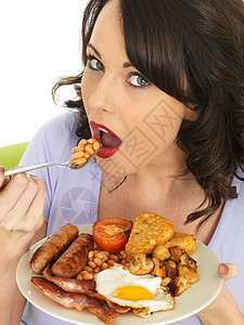 正在吃全英语早餐的女青年盘子冒充香肠黑发女士食物成人油炸摄影熏肉图片