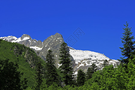 白雪和清蓝天空下高加索山脉滑冰岩石天空冻结荒野旅行蓝色天蓝色石头森林图片