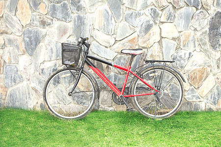 紧靠墙壁的旧红色自行车图片