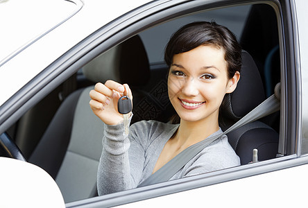 坐在显示钥匙的车里的漂亮女孩销售量驾驶成人女性青少年车轮运输微笑快乐汽车图片