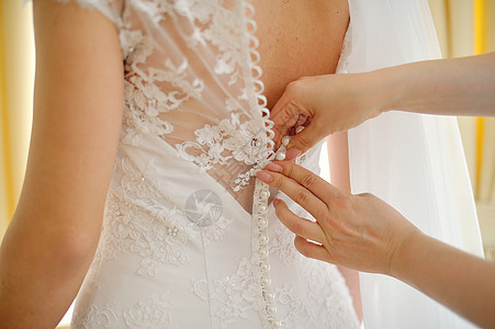 伴娘在帮新娘穿衣服女性设计师装饰品裙子青年胸衣蕾丝丝带丝绸庆典图片